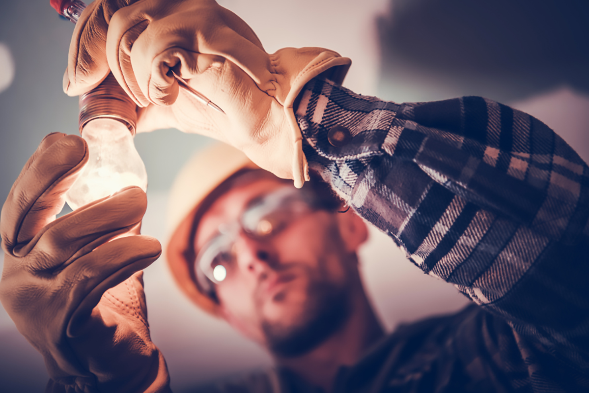 Elettricista che fissa la luce all'interno dell'appartamento ristrutturato. Tema di costruzione.