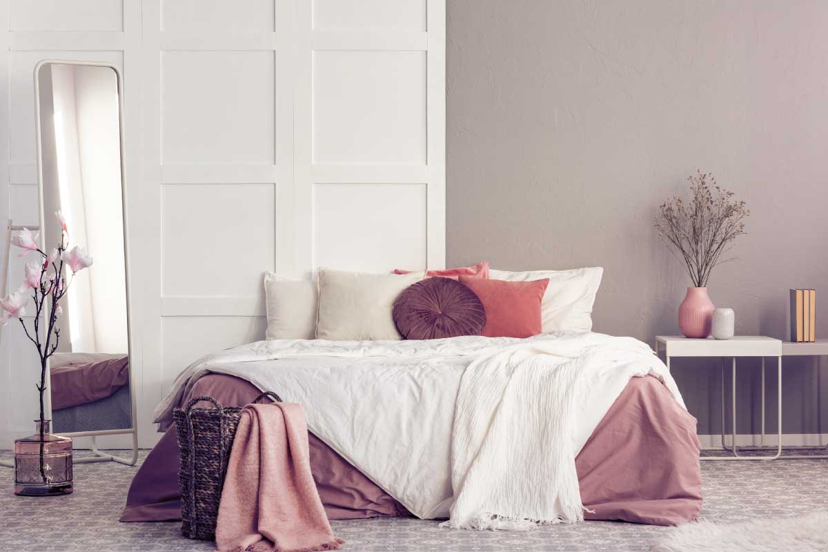 Camera degli ospiti con letto matrimoniale, coperte rosa e boiserie bianca