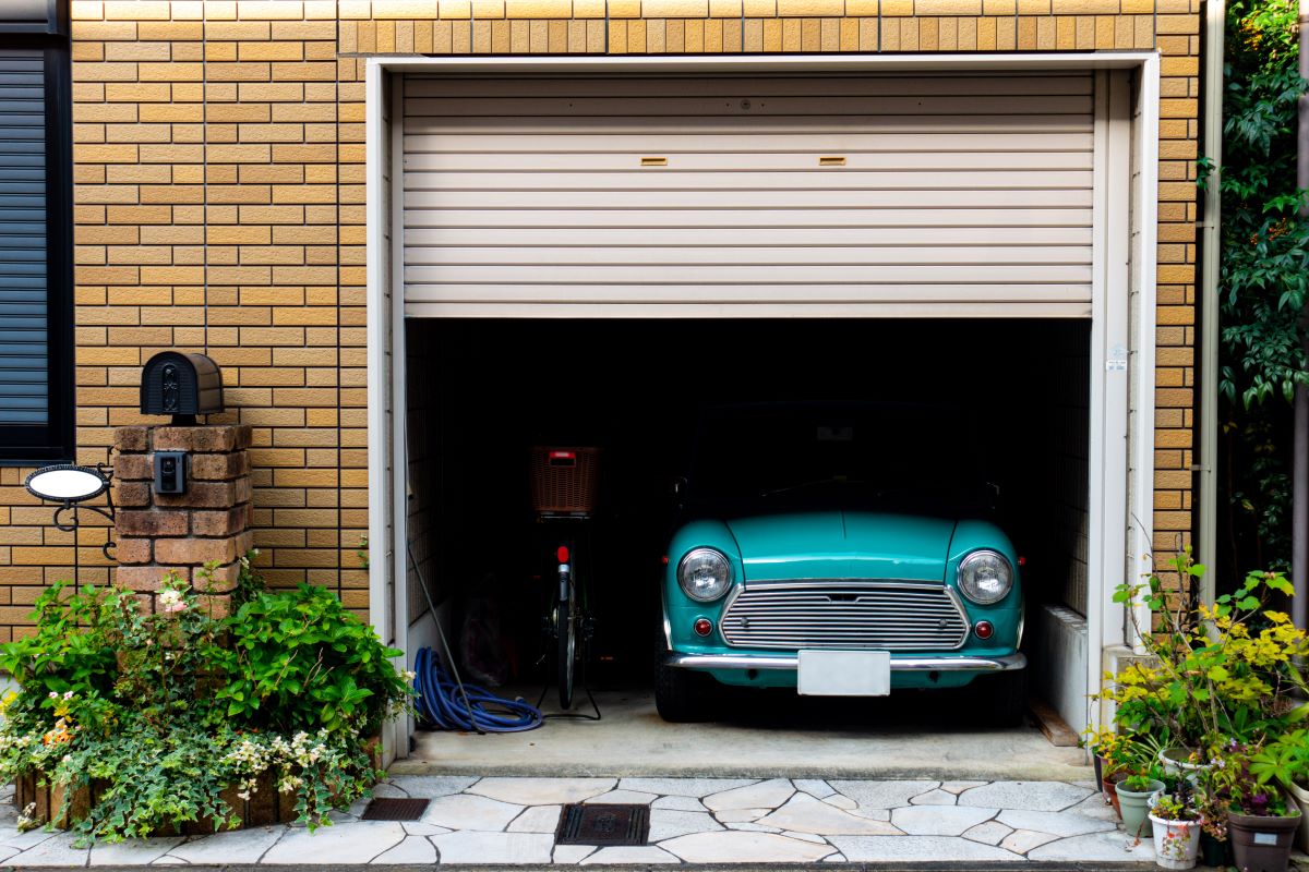 Garage in mattoni con la serranda aperta e un'auto d'epoca