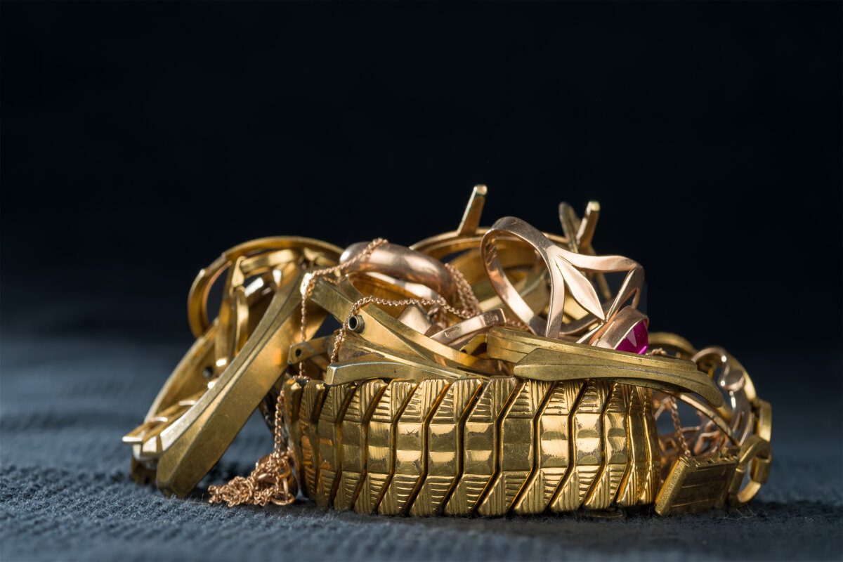 Bracciali e catene d'oro ammucchiati su un fondo scuro