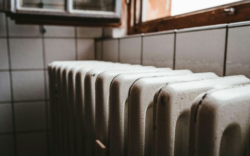 Termosifone in ghisa bianco sotto una finestra con il davanzale in legno