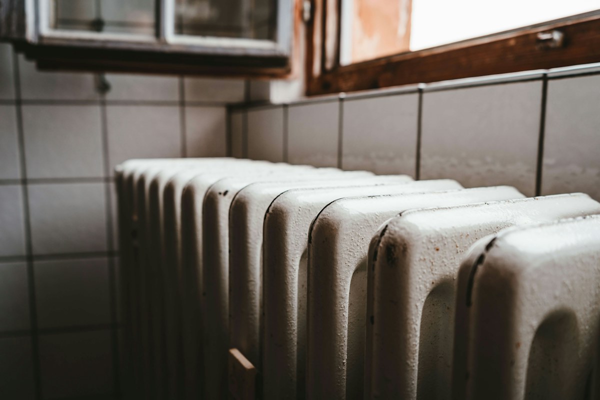 Termosifone in ghisa bianco sotto una finestra con il davanzale in legno