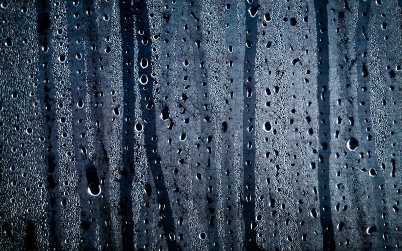 Gocce di condensa e acqua su un vetro con luci sfocate sullo sfondo