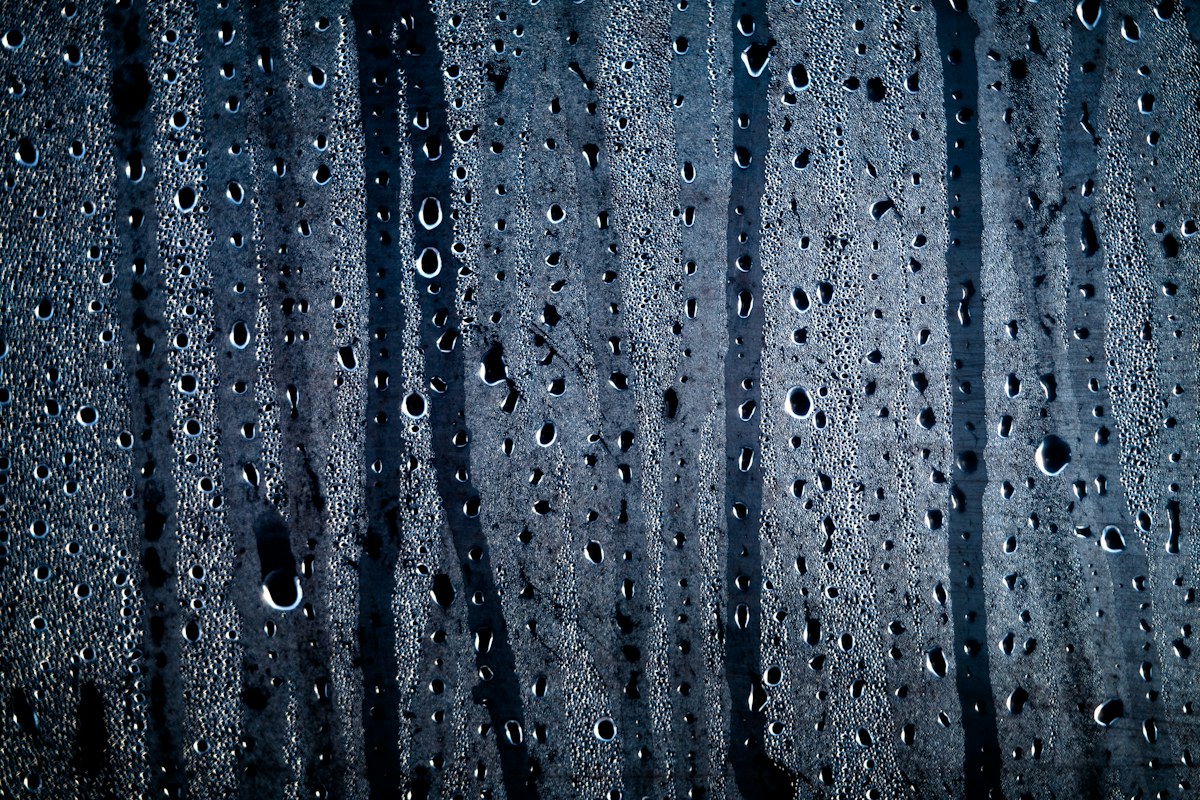 Gocce di condensa e acqua su un vetro con luci sfocate sullo sfondo