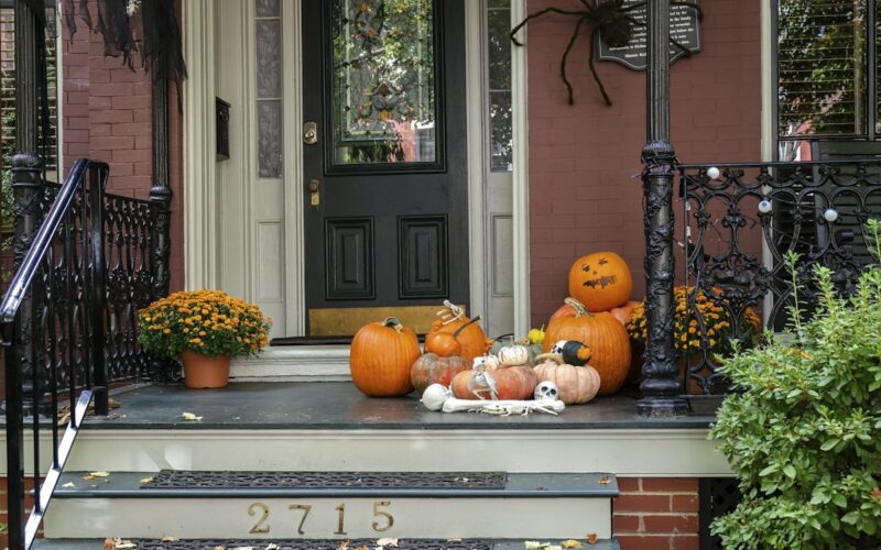 Ingresso di casa decorato per Halloween con zucche e fiori sui gradini