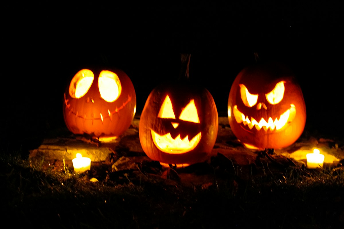 Tre zucche intagliate illuminate nel buio con piccole luci accanto