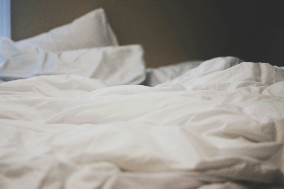 Dettaglio di un piumone bianco morbido e di un cuscino su un letto disfatto