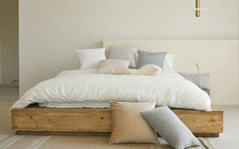 Letto matrimoniale con piumone bianco, cuscini e struttura in legno chiaro