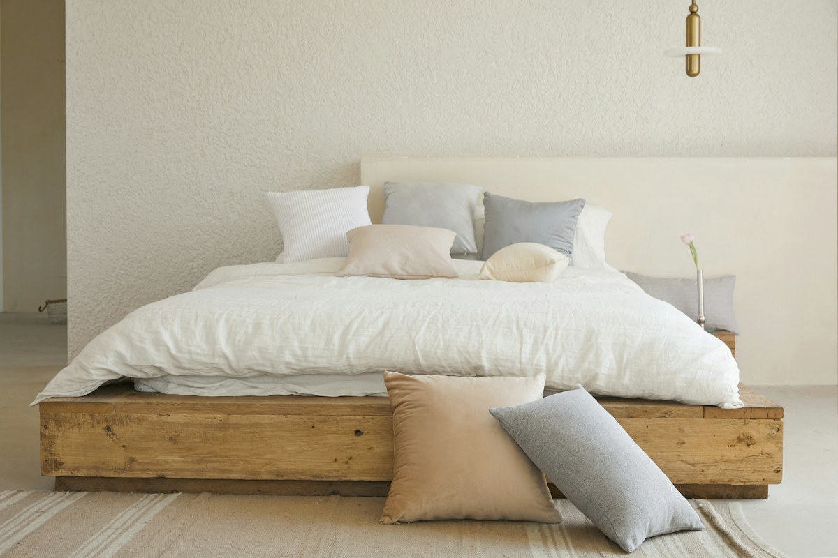 Letto matrimoniale con piumone bianco, cuscini e struttura in legno chiaro