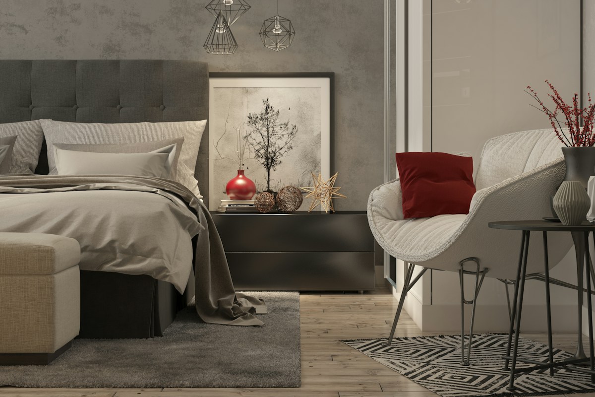 Camera da letto in toni neutri con un cuscino rosso sulla poltrona bianca