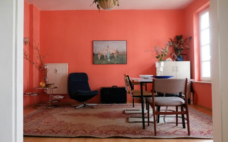 Soggiorno con pareti rosso corallo, tavolo in legno, sedie scure e tappeto