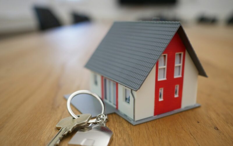 Modellino di casa con tetto grigio e un mazzo di chiavi su un tavolo di legno