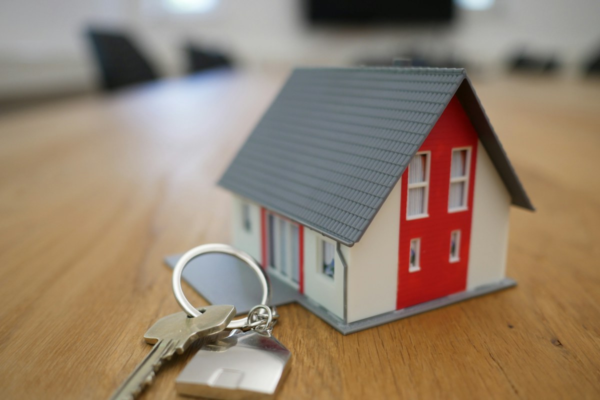 Modellino di casa con tetto grigio e un mazzo di chiavi su un tavolo di legno