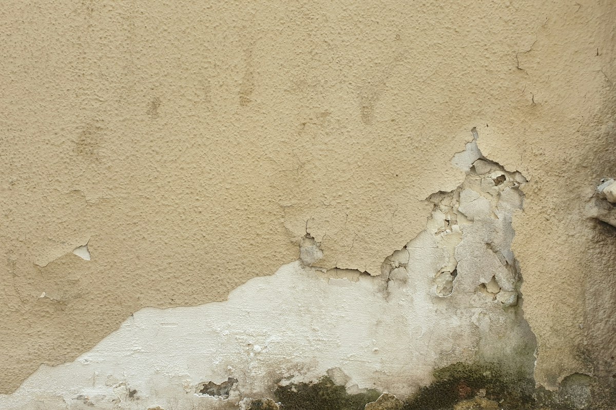 Parete con intonaco rovinato dall'umidità e pittura che si stacca