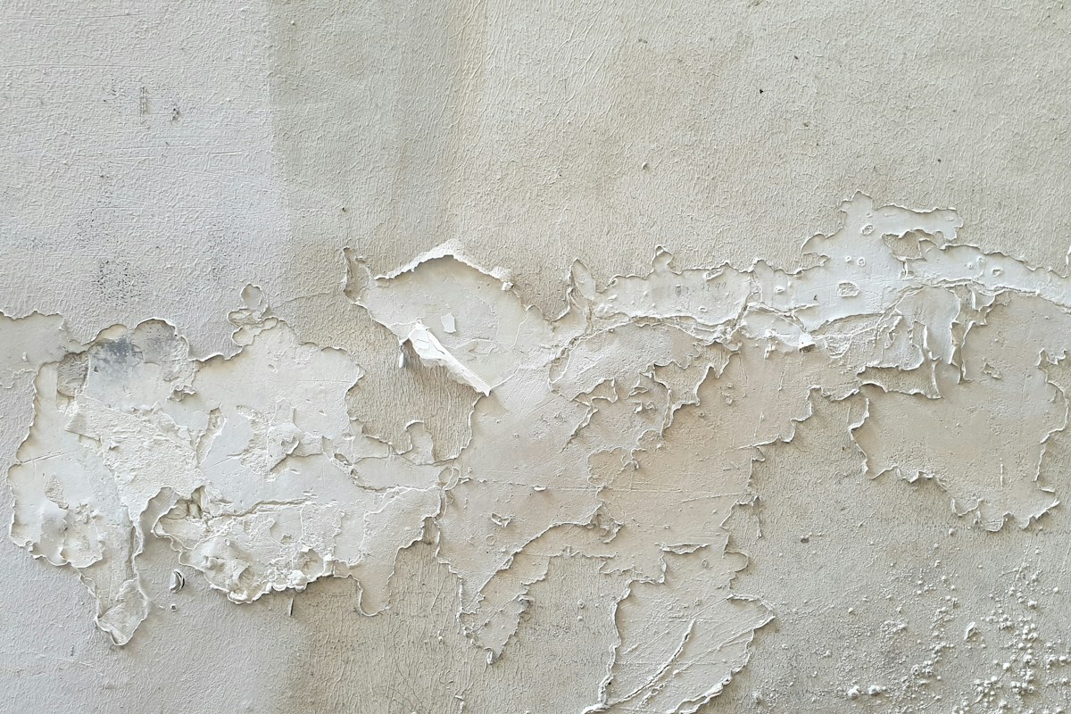 Parete bianca con pittura scrostata dall'umidità